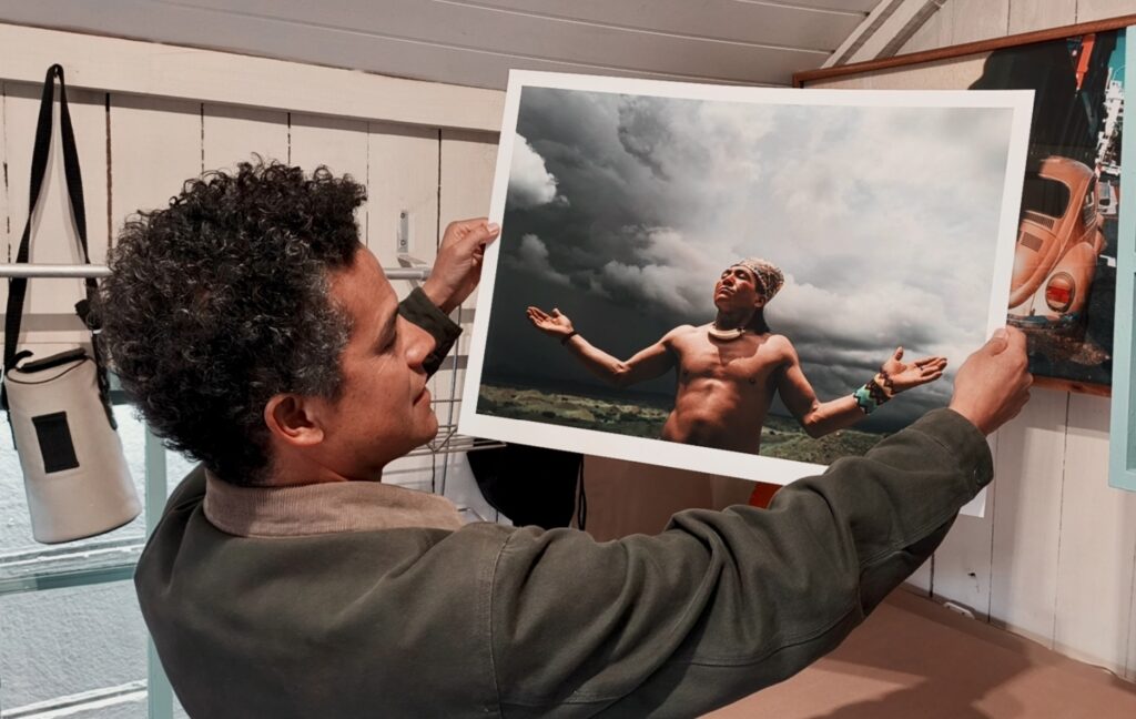 Photographer Gary van Wyk holding a large print of the same portrait in his studio.