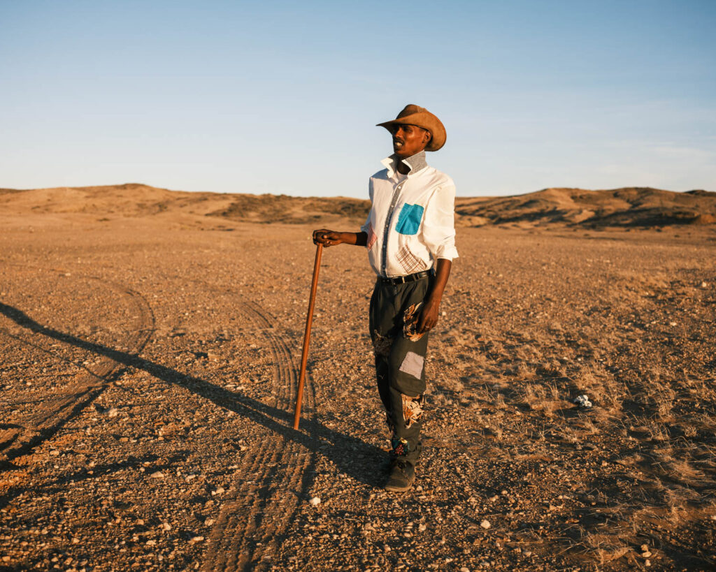 Stoftrap dancer standing with a walking stick in the arid Richtersveld landscape during the filming of Out of Mined.
